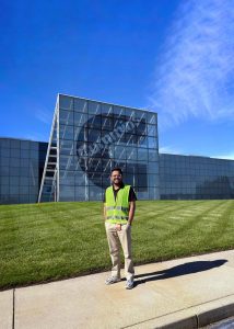 Aditya Prakash standing outside the Cummins plant in a yellow safety vest.