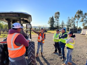 Tyler next to a tractor with a team wearing safety vests.